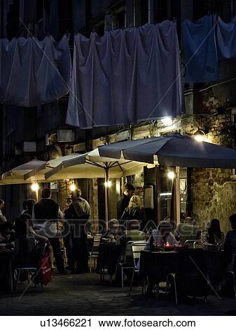 Venetian style restaurant: people dining in street restaurant with night illumination, and laundry hanging overhead, Venice, Italy View Large Photo Image Stock Image - Venetian style restaurant: people dining in street restaurant with night illumination, and laundry hanging overhead, Venice, Italy. Fotosearch