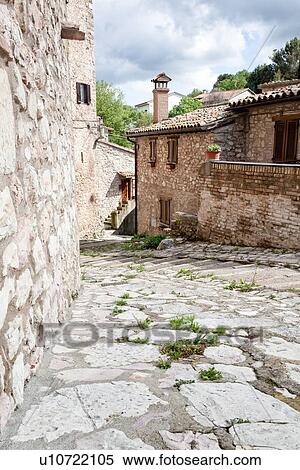 Stock Photography - Viepri: stone-paved village street leading down steps to stone houses, afternoon spring light, Umbria, Italy. Fotosearch