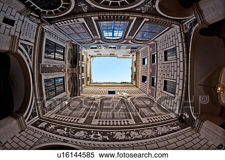 Stock Photography - View looking straight upwards in courtyard of palazzo, decorated entirely with faux architectural trompe d'oeil designs of French windows, brick, balconies from floor to ceiling, open to blue sky, Rome, Italy. Fotosearch