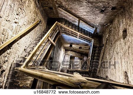 Stock Image - View of interior of Torre Asinelli, (one of the twin towers) looking down the winding wooden staircase, desaturated view, Bologna, Italy. Fotosearch
