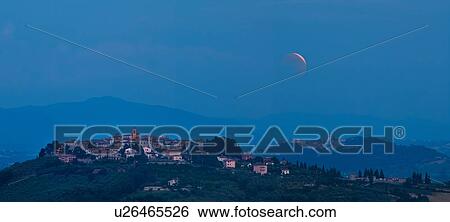 Stock Photograph - View of medieval hilltop town of MonteCastello di Vibio, with Todi in distance, dusk with huge pink full moon crescent shaped as it rises through clouds, Umbria, Italy. Fotosearch