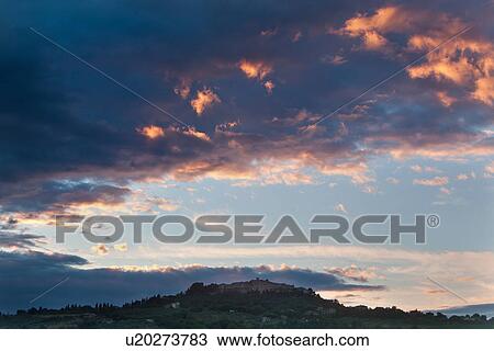 Stock Image - View of MonteCastello di Vibio hilltop town at sunset with dramatic red and grey billowing clouds, panorama view, Umbria, Italy. Fotosearch