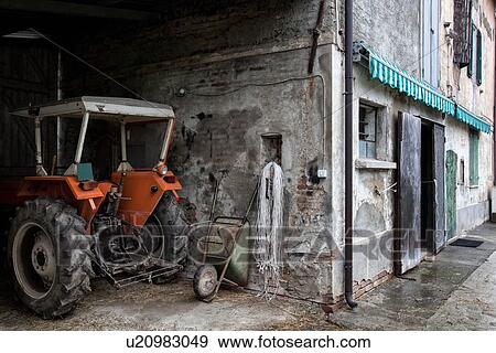 View of old stucco house and barn with orange tractor parked in foreground, house with crumbling facade, door with wooden shutters half open, green wooden shutter over window and storage door, with green and white awning, all paint peeling, typical style View Large Photo Image Stock Photo - View of old stucco house and barn with orange tractor parked in foreground, house with crumbling facade, door with wooden shutters half open, green wooden shutter over window and storage door, with green and white awning, all paint peeling, typical style. Fotosearch