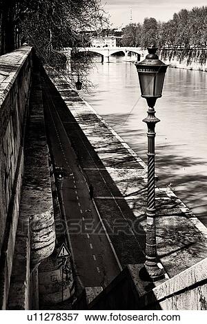 View of Ponte Mazzini, with three arches of white stone spanning River Tiber, with Lungotevere and single runner on lined path, metal lampstand in foreground, monochrome image, Rome Italy View Large Photo Image Stock Photo - View of Ponte Mazzini, with three arches of white stone spanning River Tiber, with Lungotevere and single runner on lined path, metal lampstand in foreground, monochrome image, Rome Italy. Fotosearch