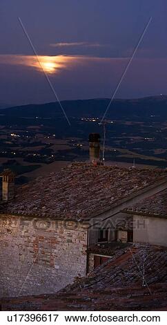 View over traditionally red-tiled terracotta rooftops and streets of medieval stone village to hills beyond Tiber valley at dusk with yellow rising full moon in indigo blue sky, Umbria, Italy View Large Photo Image Stock Photo - View over traditionally red-tiled terracotta rooftops and streets of medieval stone village to hills beyond Tiber valley at dusk with yellow rising full moon in indigo blue sky, Umbria, Italy. Fotosearch