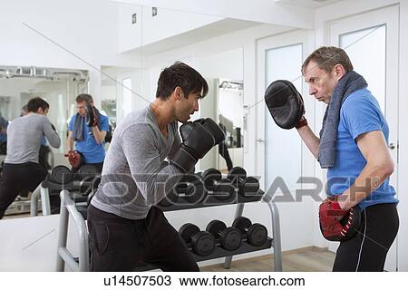 Boxer practicing with trainer in gym View Large Photo Image Stock Image - Boxer practicing with trainer in gym. Fotosearch