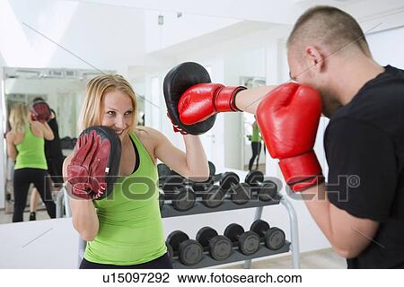 Stock Image - Boxer working with trainer in gym. Fotosearch