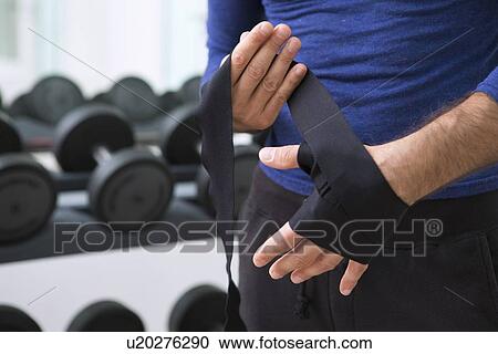 Stock Image - Boxer wrapping his hands in gym. Fotosearch