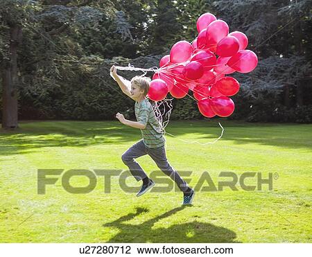 Boy carrying bunch of balloons outdoors View Large Photo Image Stock Image - Boy carrying bunch of balloons outdoors. Fotosearch