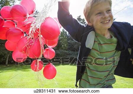 Boy carrying bunch of balloons outdoors View Large Photo Image Stock Image - Boy carrying bunch of balloons outdoors. Fotosearch