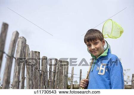 Stock Image - Boy carrying butterfly nets outdoors. Fotosearch