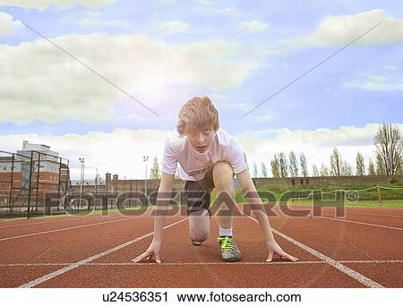 Stock Image - Boy crouched at starting line on track. Fotosearch