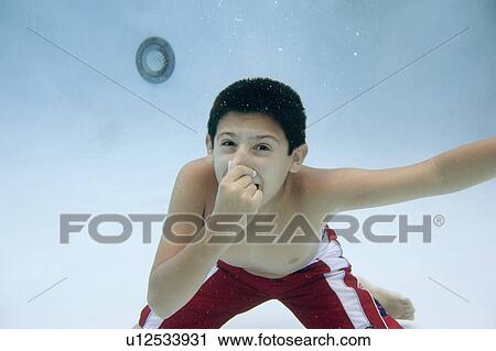 Stock Image - Boy holding nose underwater. Fotosearch