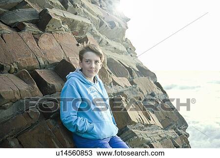 Boy leaning on rock formation on beach View Large Photo Image Stock Image - Boy leaning on rock formation on beach. Fotosearch
