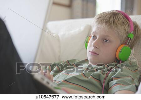 Stock Photo - Boy listening to headphones on laptop. Fotosearch