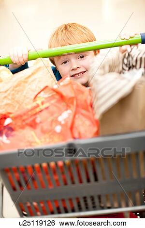 Stock Photograph - Boy pushing cart in grocery store. Fotosearch