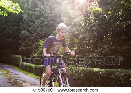 Stock Image - Boy riding bicycle on rural road. Fotosearch