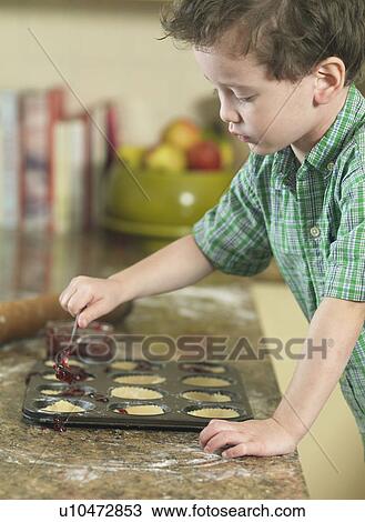 Boy spooning batter into pan in kitchen View Large Photo Image Stock Image - Boy spooning batter into pan in kitchen. Fotosearch