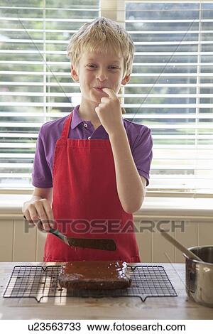 Boy tasting cake frosting in kitchen View Large Photo Image Stock Image - Boy tasting cake frosting in kitchen. Fotosearch