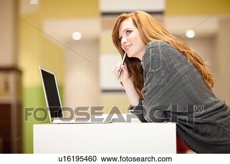 Stock Image - Businesswoman using computer at desk. Fotosearch