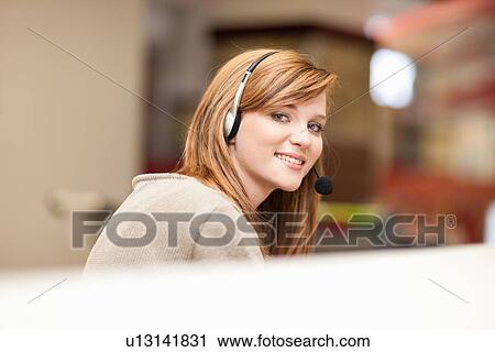 Stock Image - Businesswoman wearing headset in office. Fotosearch