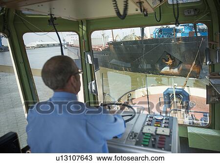 Captain steering tugboat in wheelhouse View Large Photo Image Stock Image - Captain steering tugboat in wheelhouse. Fotosearch