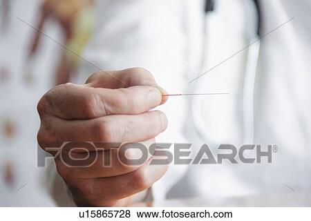 Stock Photo - Close up of doctor holding needle. Fotosearch