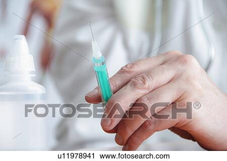 Stock Image - Close up of doctor holding syringe. Fotosearch