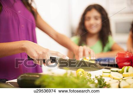 Picture - Close up of woman slicing vegetables. Fotosearch