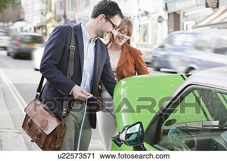 Couple charging electric car on street View Large Photo Image Stock Image - Couple charging electric car on street. Fotosearch