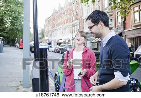 Couple charging electric car on street View Large Photo Image Stock Photography - Couple charging electric car on street. Fotosearch