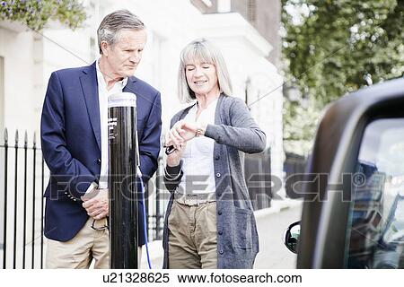 Couple charging electric car on street View Large Photo Image Stock Photography - Couple charging electric car on street. Fotosearch