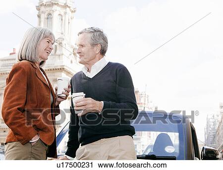 Couple drinking coffee on city street View Large Photo Image Stock Image - Couple drinking coffee on city street. Fotosearch