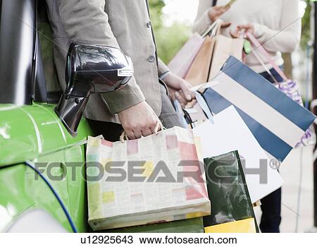Stock Image - Couple loading shopping bags in car. Fotosearch