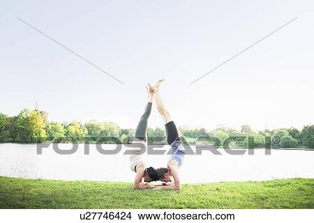 Picture - Couple practicing yoga by water. Fotosearch