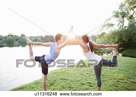 Stock Photo - Couple practicing yoga by water. Fotosearch