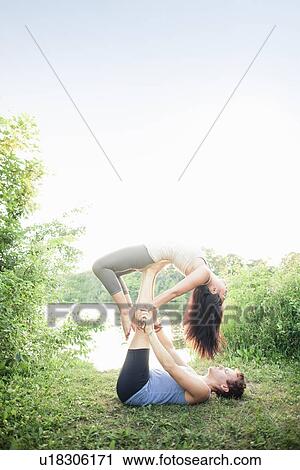 Stock Image - Couple practicing yoga in garden. Fotosearch