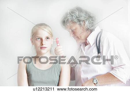 Stock Image - Doctor checking girl’s inner ear. Fotosearch