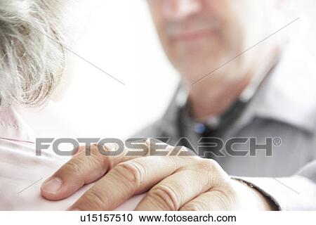 Stock Image - Doctor with hand on patient’s shoulder. Fotosearch