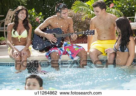 Family relaxing by swimming pool View Large Photo Image Stock Image - Family relaxing by swimming pool. Fotosearch