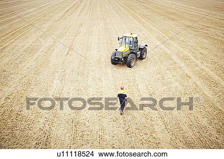 Farmer walking to tractor in crop field View Large Photo Image Picture - Farmer walking to tractor in crop field. Fotosearch