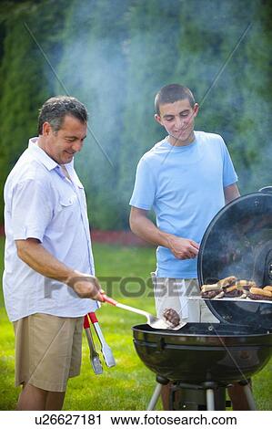 Father and son grilling outdoors View Large Photo Image Stock Image - Father and son grilling outdoors. Fotosearch