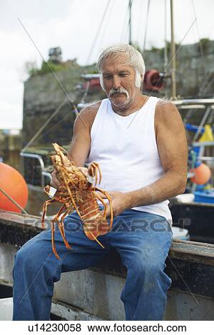 Stock Photo - Fisherman holding lobster on boat. Fotosearch