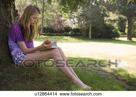 Girl eating apple and reading in park View Large Photo Image Picture - Girl eating apple and reading in park. Fotosearch