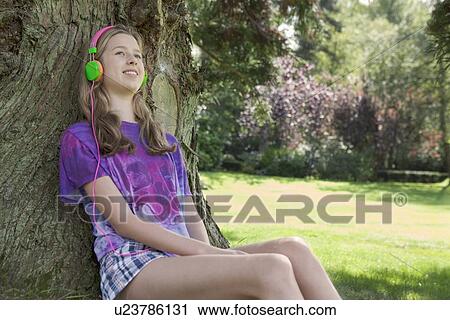 Girl listening to headphones in park View Large Photo Image Stock Image - Girl listening to headphones in park. Fotosearch