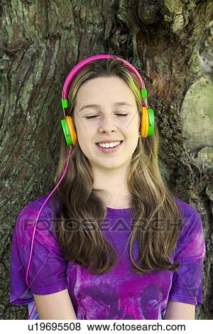 Girl listening to headphones in park View Large Photo Image Stock Photo - Girl listening to headphones in park. Fotosearch