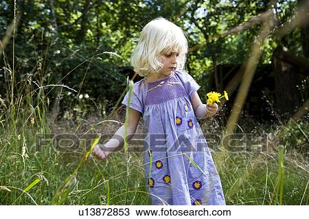 Stock Image - Girl picking flowers outdoors. Fotosearch