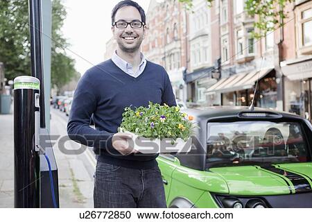 Man carrying flowerbox on city street View Large Photo Image Stock Image - Man carrying flowerbox on city street. Fotosearch