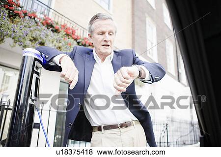 Man charging electric car on street View Large Photo Image Stock Photo - Man charging electric car on street. Fotosearch