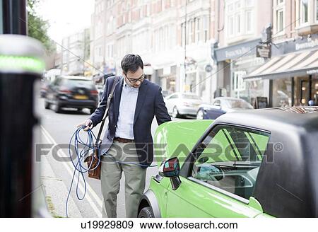 Man charging electric car on street View Large Photo Image Stock Photo - Man charging electric car on street. Fotosearch
